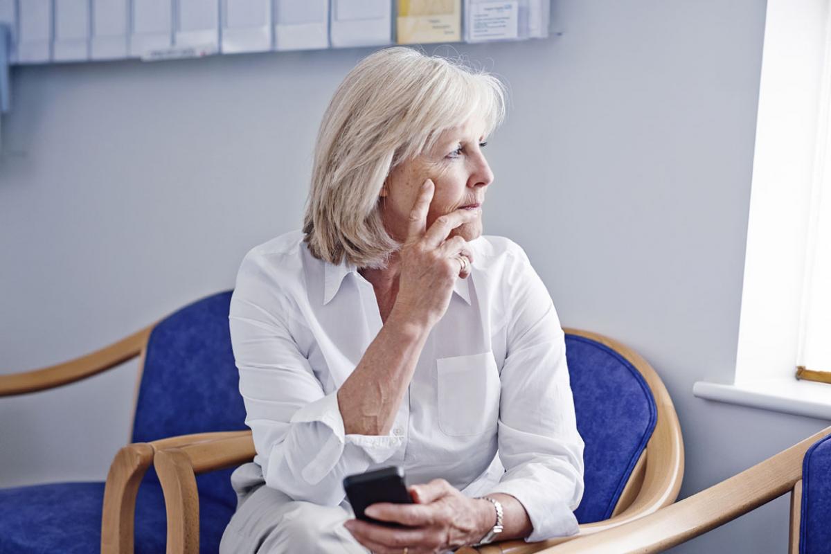 Patient holds device as she looks pensively out the window. 